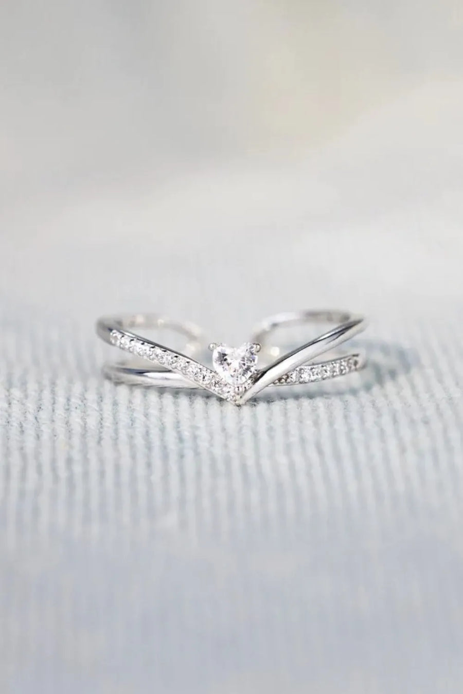 Silver V-shaped ring with diamond accents and a central heart-shaped diamond.