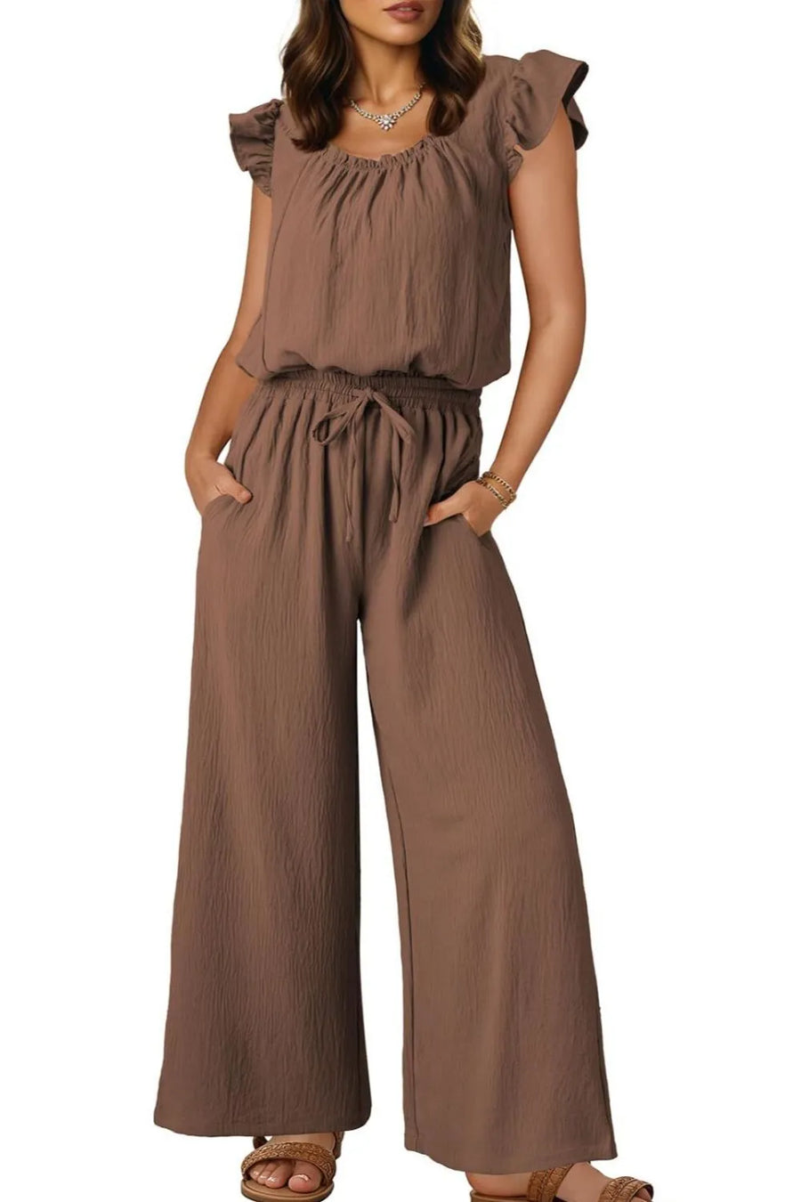 Taupe textured drawstring palazzo jumpsuit with ruffle sleeves and wide legs.