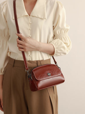 crossbody bag in cognac featuring metal emblem and structured fit