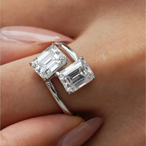 Emerald-cut moissanite bypass ring in silver with two radiant stones.