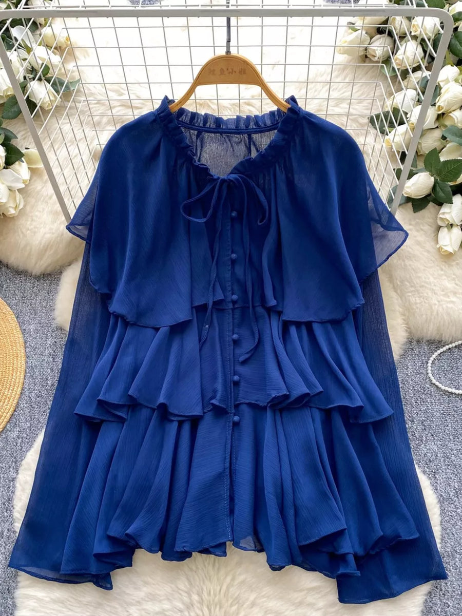 Blue chiffon tiered shirt with ruffled details and bow tie neckline.
