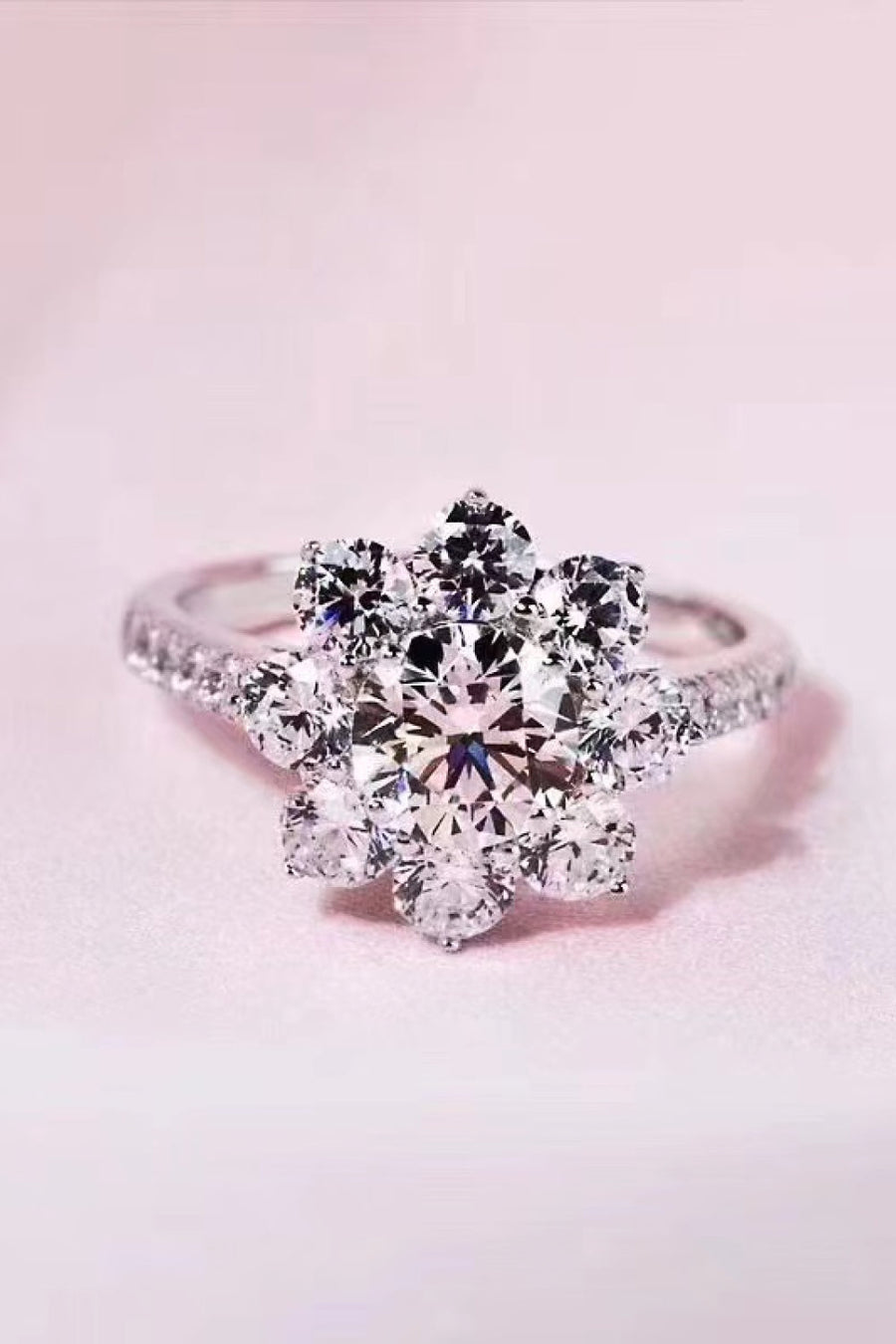 Silver moissanite engagement ring with a petal cluster design and pavé band.