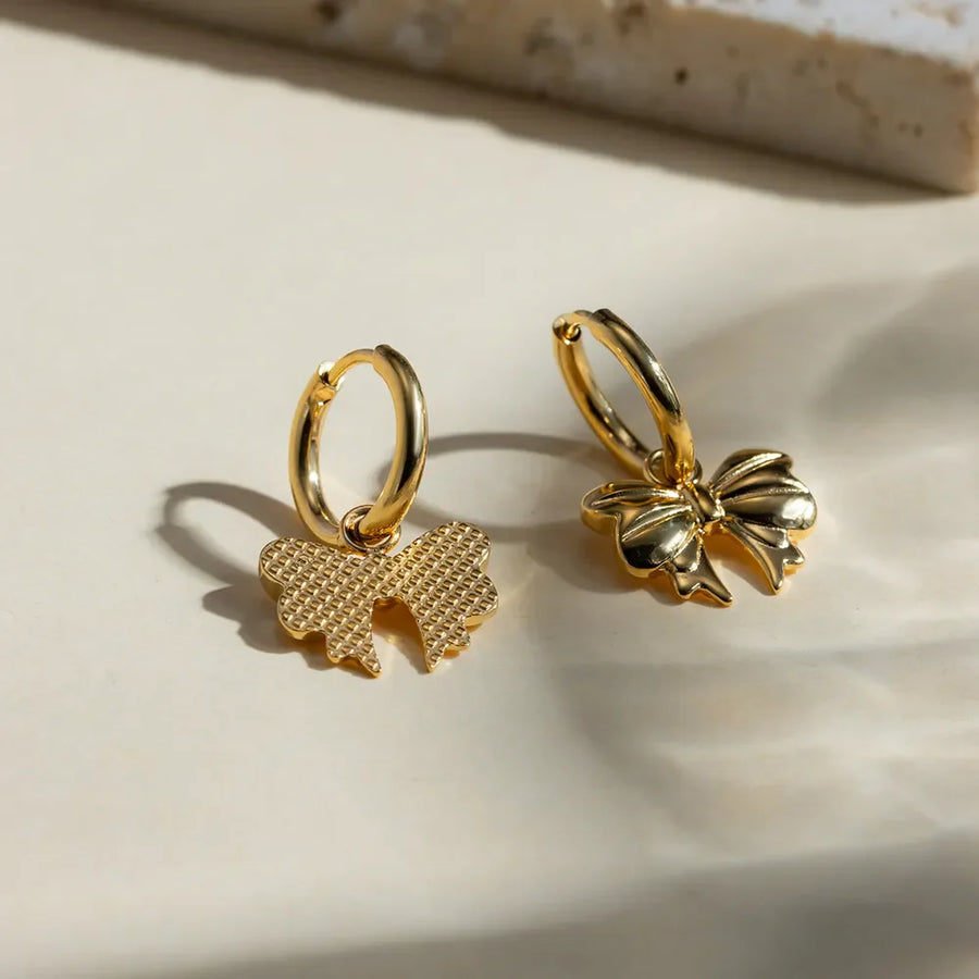 Gold hoop earrings with detailed bow charms, 18K gold-plated.