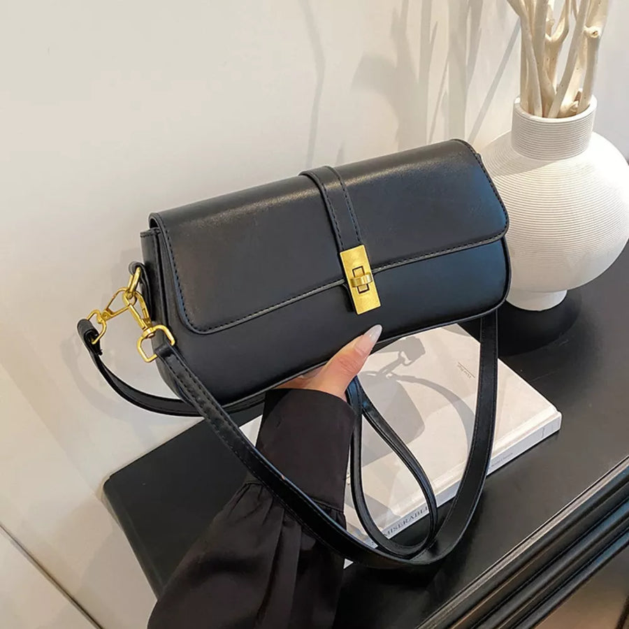 Black rectangular crossbody bag with gold clasp and adjustable strap
