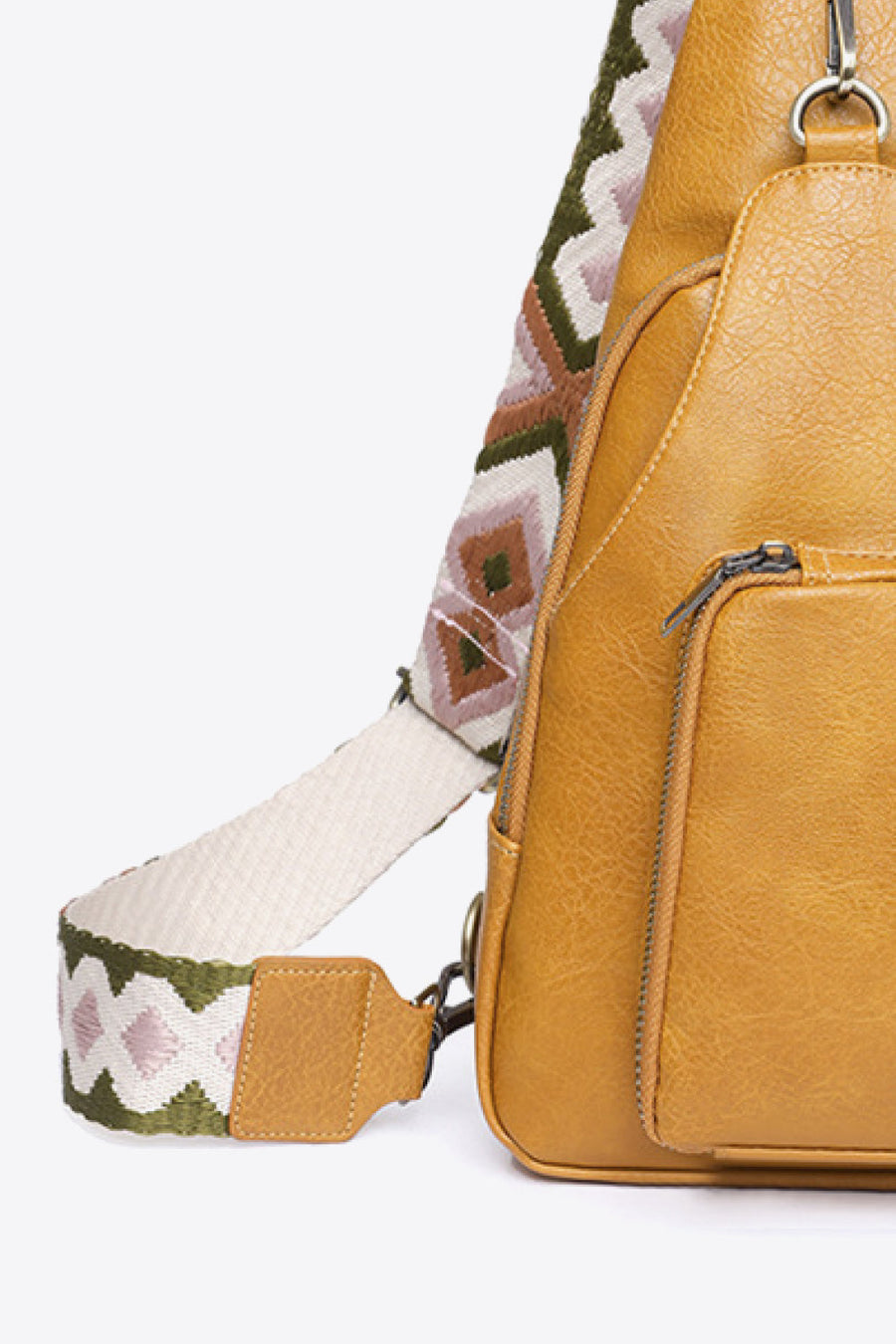 Ochre PU sling bag with a patterned strap and front zip pocket.
