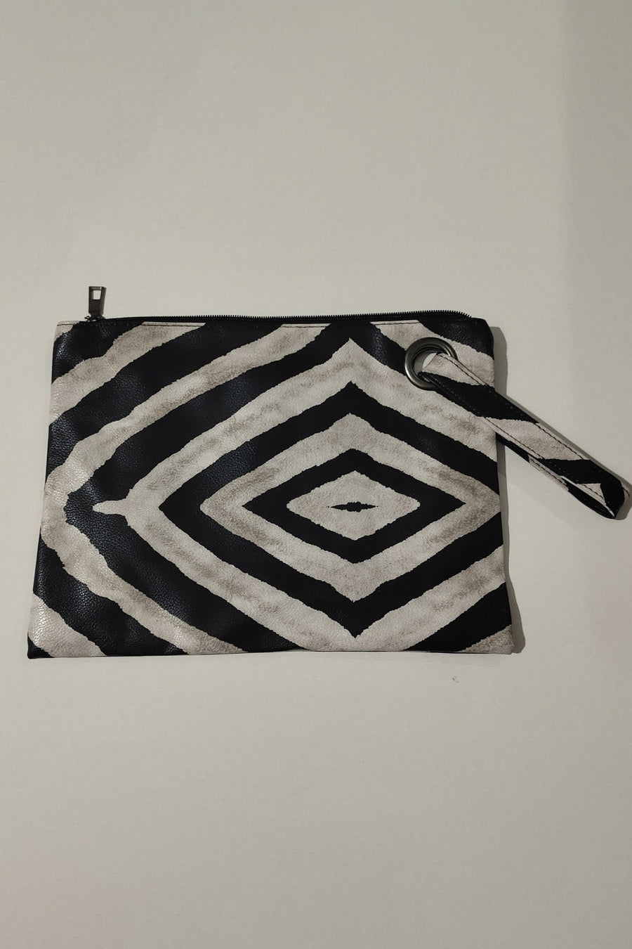 Clutch bag with black and white zebra print, wristlet strap, and grommet detail.