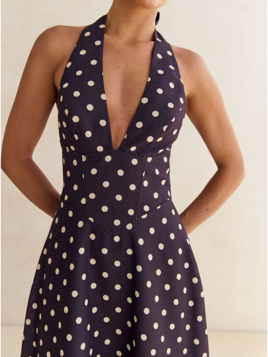 Navy polka dot halter neck maxi dress with a deep V-neck and A-line skirt.
