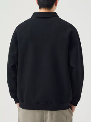 Black raglan quarter zip sweatshirt with collar and contrast stitching detail.