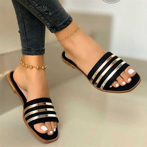 Black flat sandals with metallic stripes and open toe.