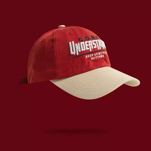 Red baseball cap with embroidered "UNDERSTAND" and "KEEP UP WITH RHYTHMS" text, beige brim.