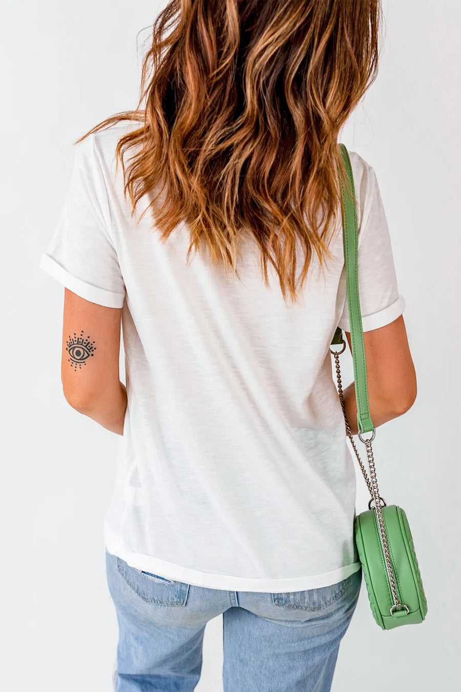 White graphic t-shirt with rolled sleeves and an eye tattoo on the arm.