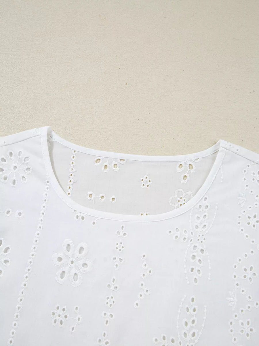 White cotton blouse with delicate eyelet embroidery and a ruffled neckline.