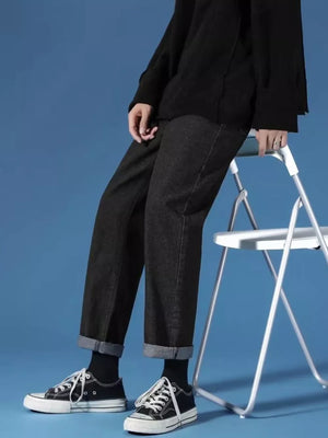 Black relaxed-fit straight-leg jeans with cuffed hems, styled with sneakers.