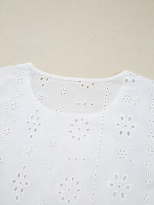 White cotton blouse with delicate eyelet embroidery and floral details.