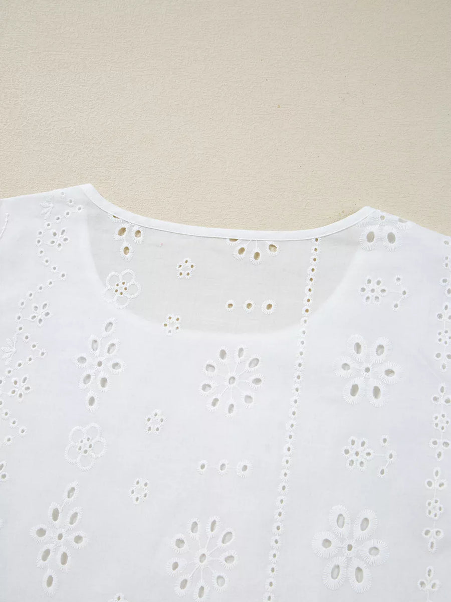 White cotton blouse with delicate eyelet embroidery and floral details.