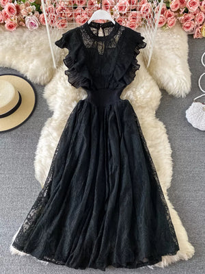Black lace maxi dress with ruffles, cutout waist, and high neckline.
