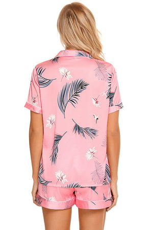 Pink botanical print satin pajama set with buttoned top and shorts.
