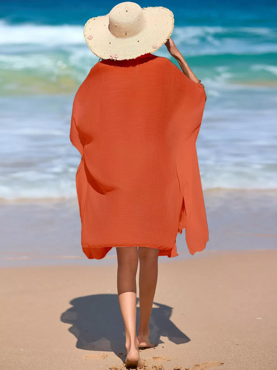 Orange button-up cover-up with side slits and a relaxed fit, worn on a beach.