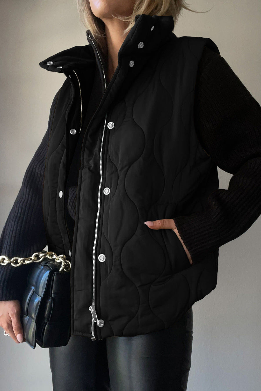 Black quilted stand-collar utility gilet with snap and zip closure.