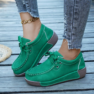 Green lace-up moccasin style sneakers with white stitching and a brown sole.