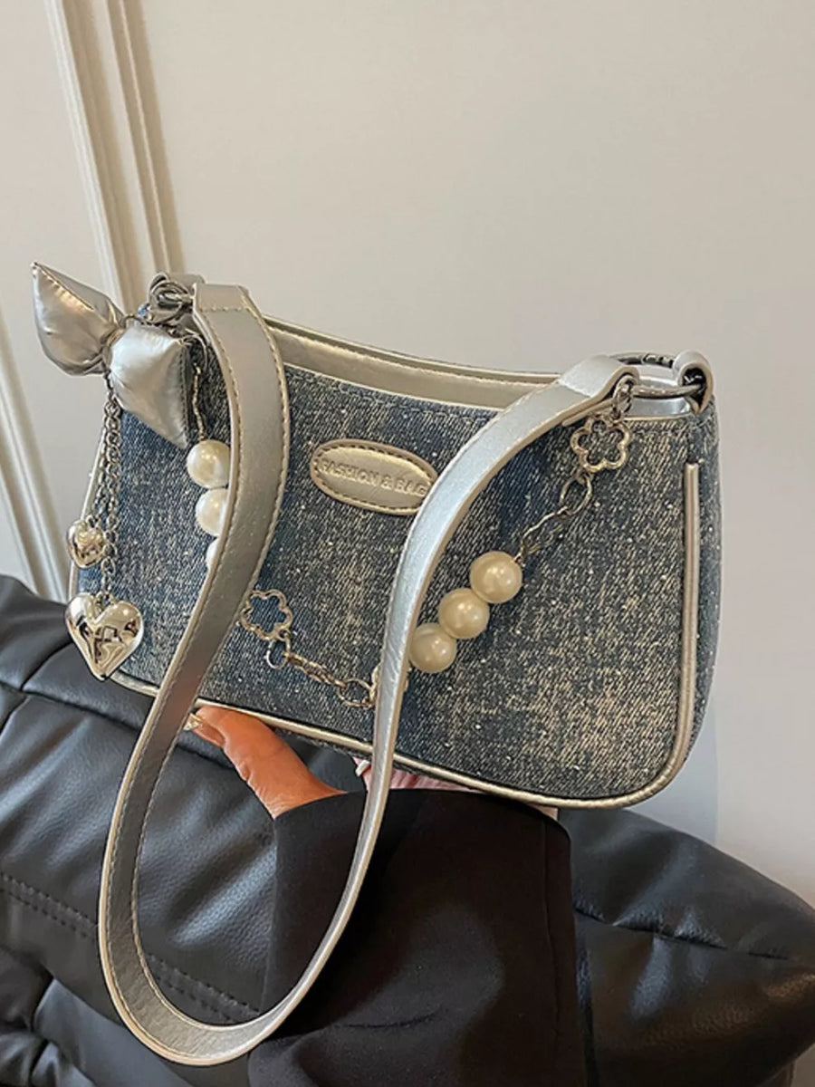 Denim shoulder bag with pearl chain, silver bow, heart and clover charms.