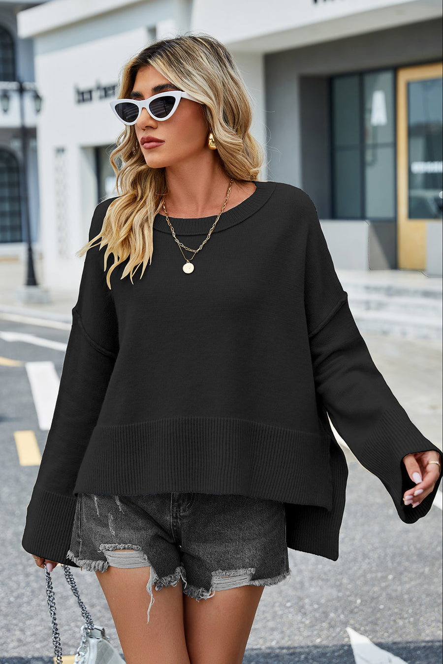 Black acrylic knit sweater with flared sleeves and split hem detail.