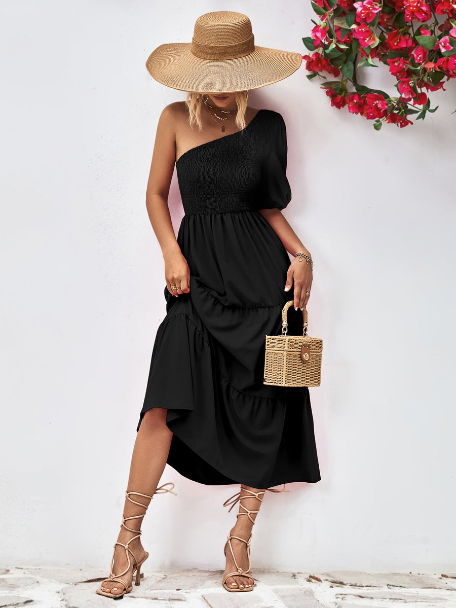 Black one-shoulder tiered dress with smocked bodice and ruffled hem.