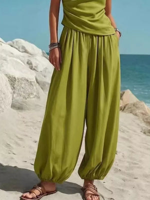 Green one-shoulder top and wide-leg pants set with pockets, styled casually.
