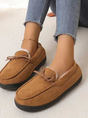 Caramel suede moccasin slippers with faux fur lining and bow detail.