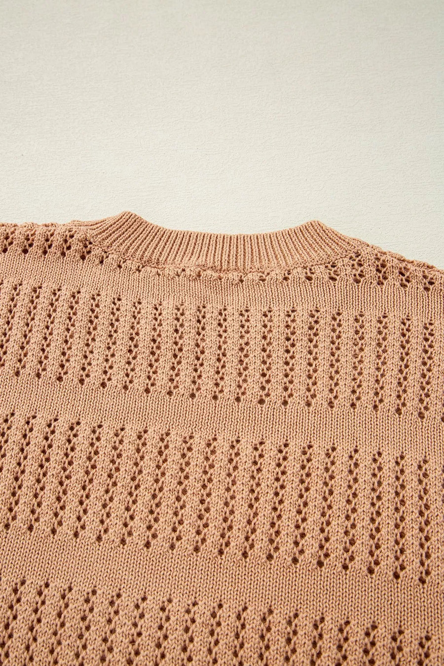 Peach openwork knit sweater with crew neck and elbow sleeves.