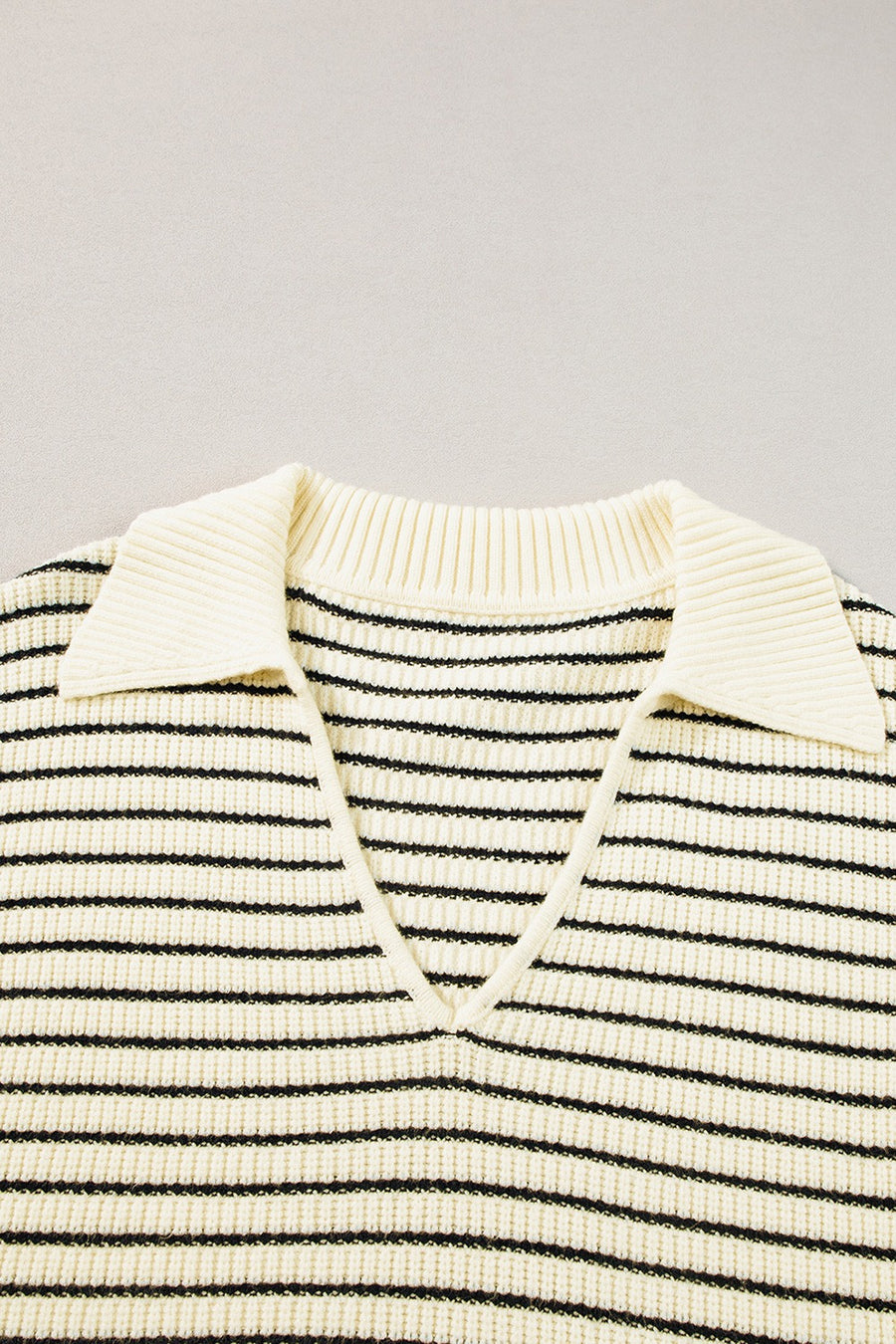 Ivory and black striped knit polo vest with a V-neck and pointed collar.