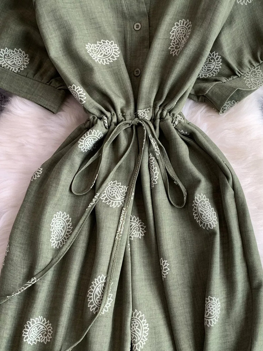 Green paisley print drawstring jumpsuit with short sleeves and button front detail.