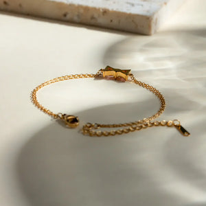 Gold chain bracelet with a gemstone bow detail and adjustable clasp.