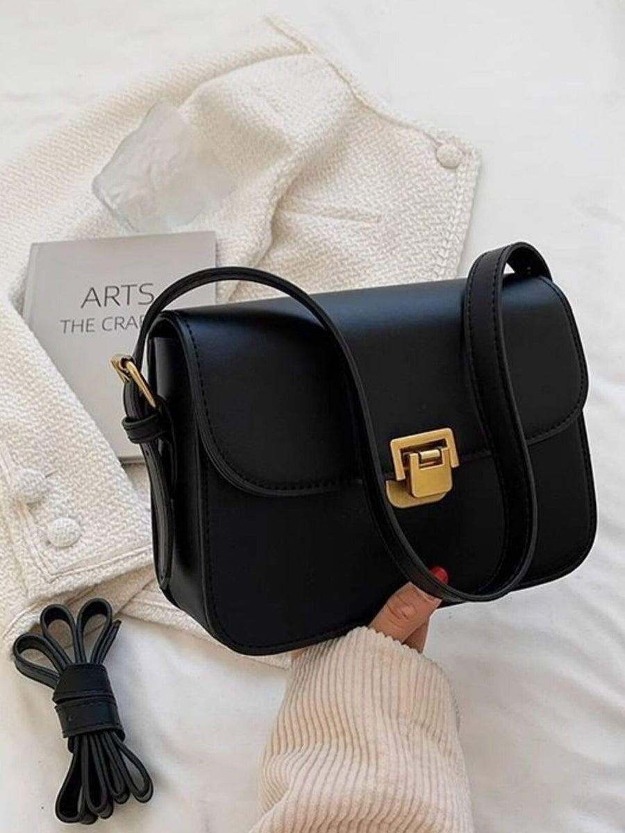 Black shoulder bag with gold buckle flap and strap detail