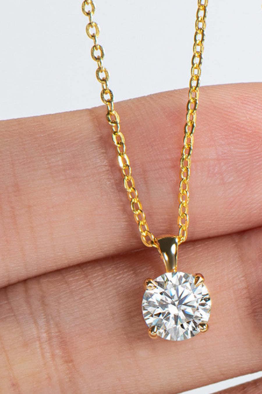 Gold chain necklace with a round solitaire diamond pendant.