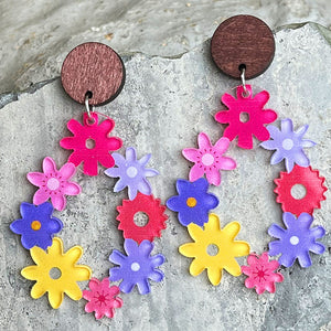 Floral wreath dangle earrings with wooden tops in pink, purple, yellow, and red acrylic flowers.