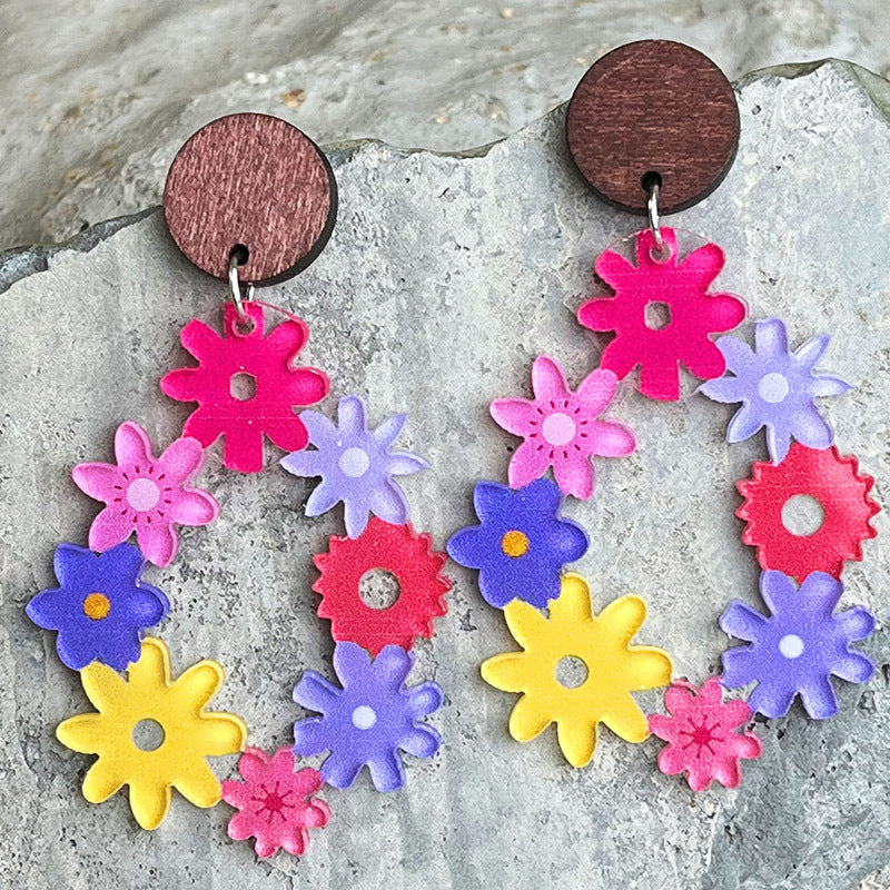 Floral wreath dangle earrings with wooden tops in pink, purple, yellow, and red acrylic flowers.