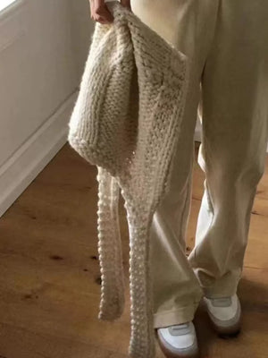 Off-white wool earflap beanie hat with long ties, chunky knit detail.