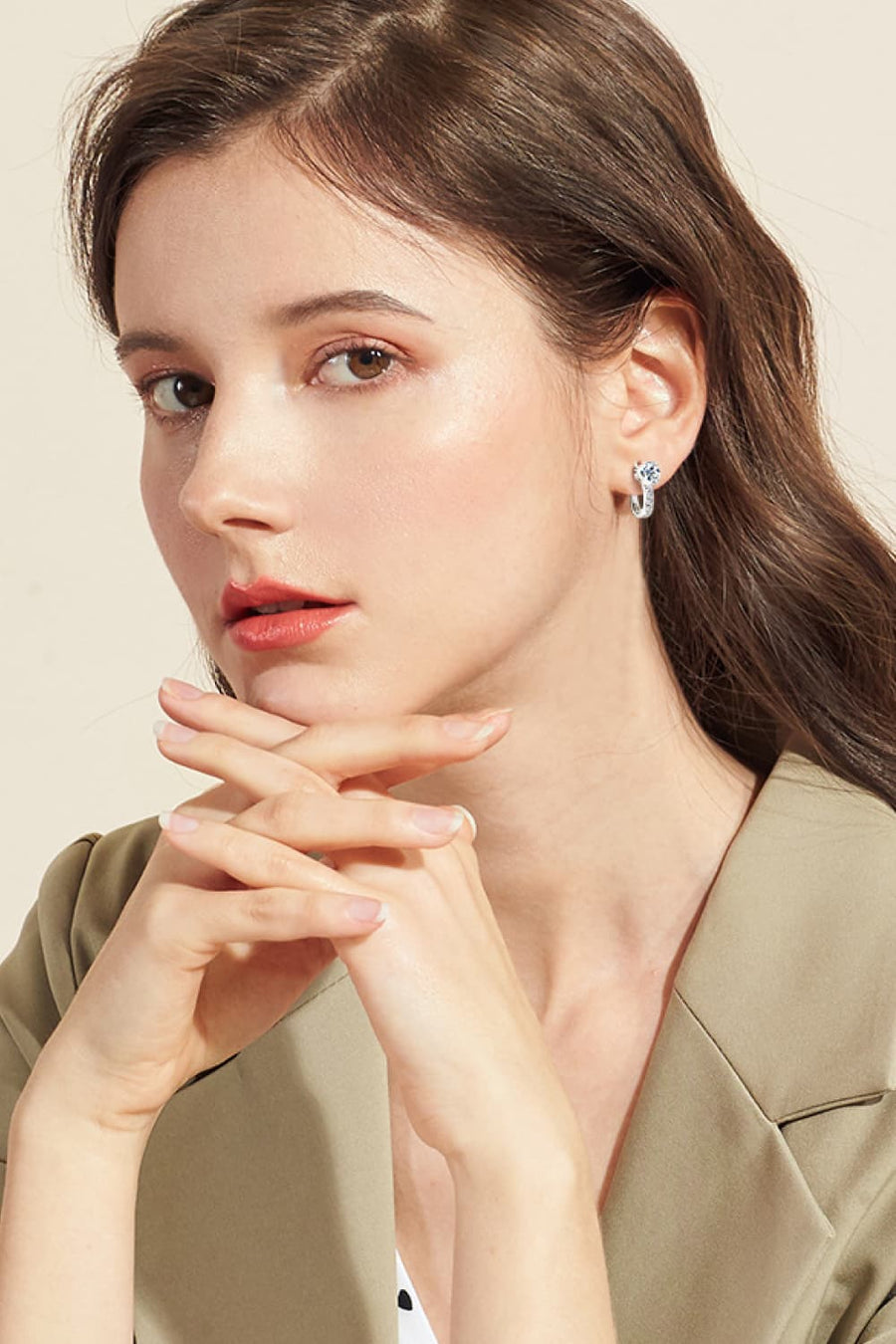 Silver pavé and solitaire hoop earrings worn by a woman.