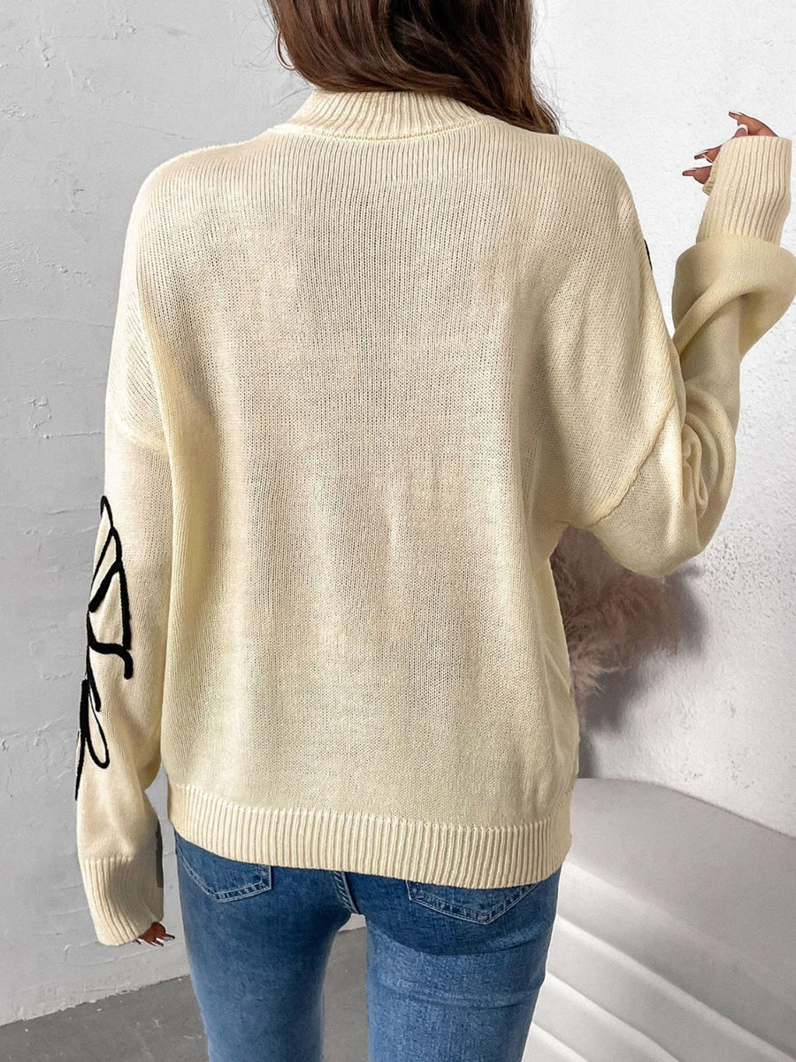 Pastel yellow acrylic knit sweater with embroidered floral motif on sleeve.