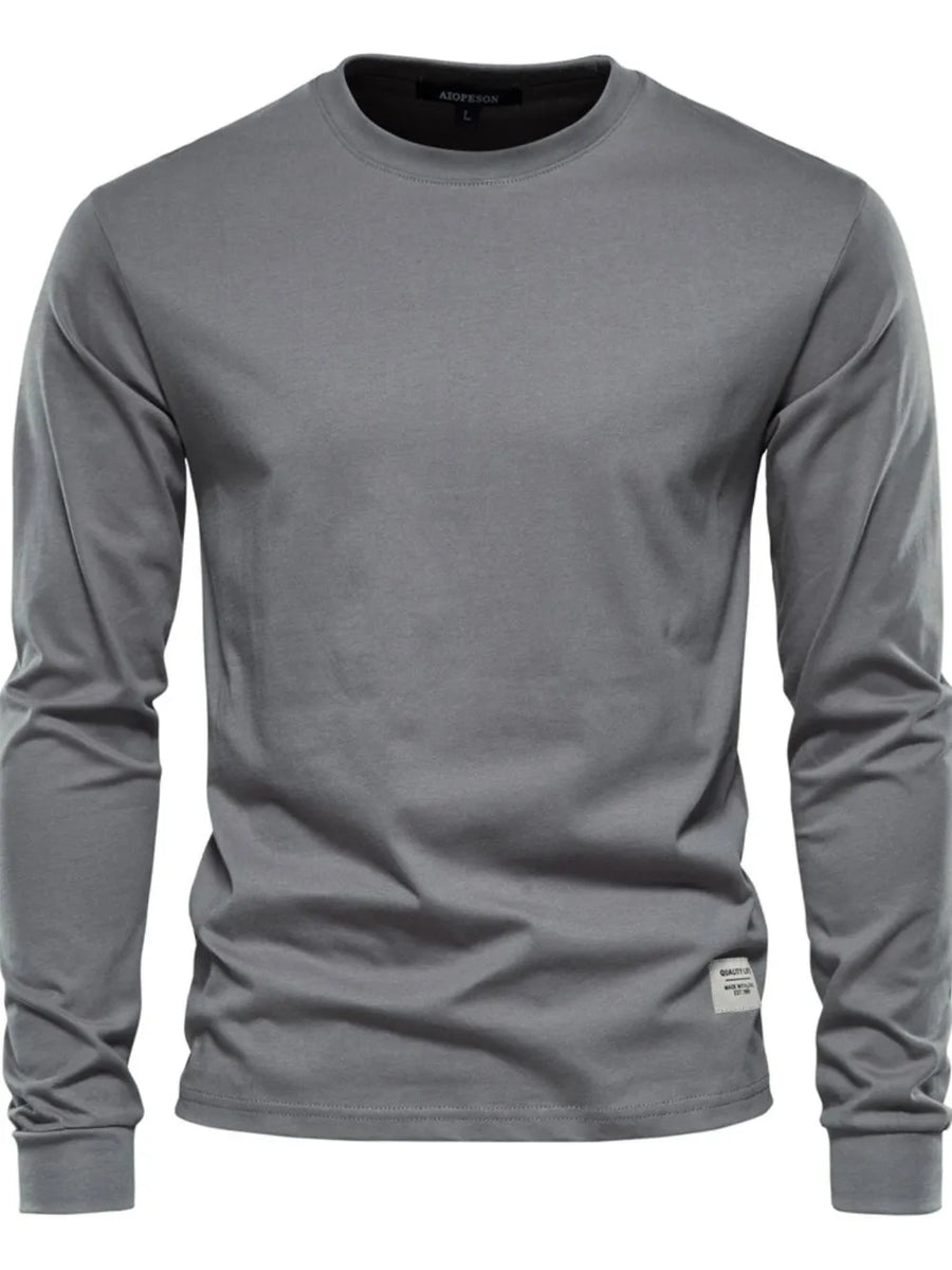 Gray crewneck long sleeve t-shirt with a small woven label detail on the hem.