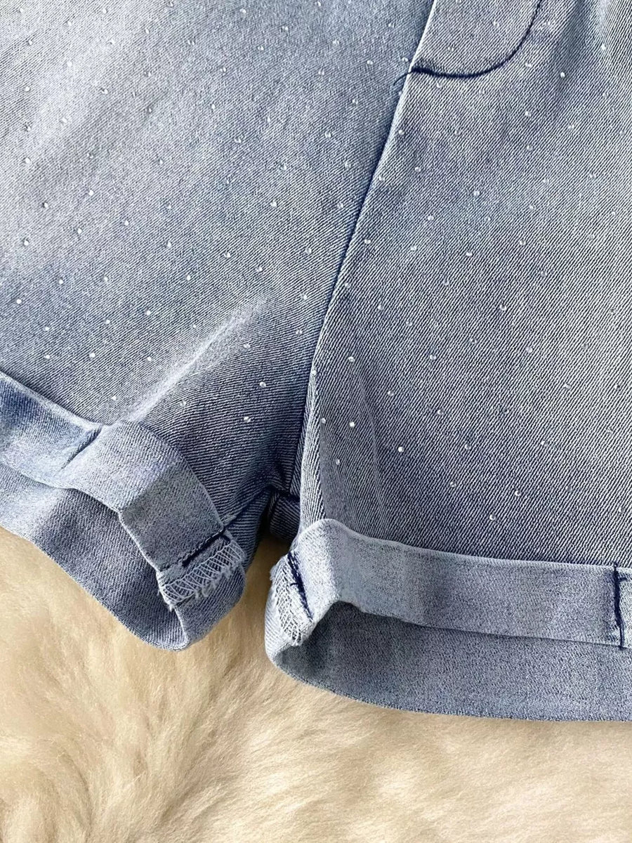 Blue denim romper with rhinestone embellishments and cuffed hems.
