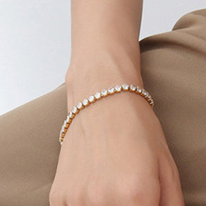 Gold pavé tennis bracelet with clear stones on a wrist.