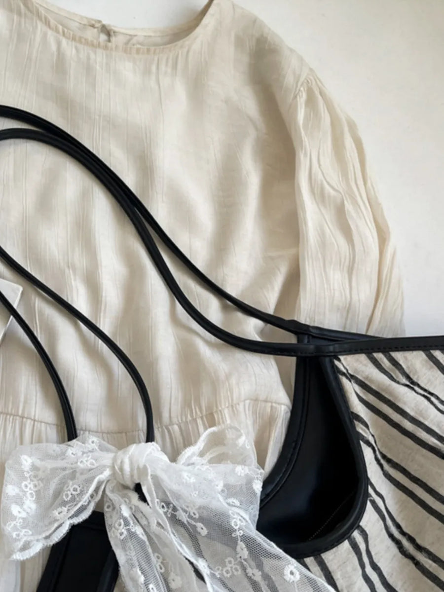 Beige shopper bag with black stripes and a white lace bow detail.