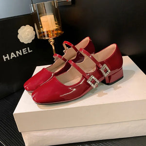 Patent leather double strap Mary Janes in scarlet with crystal buckles.