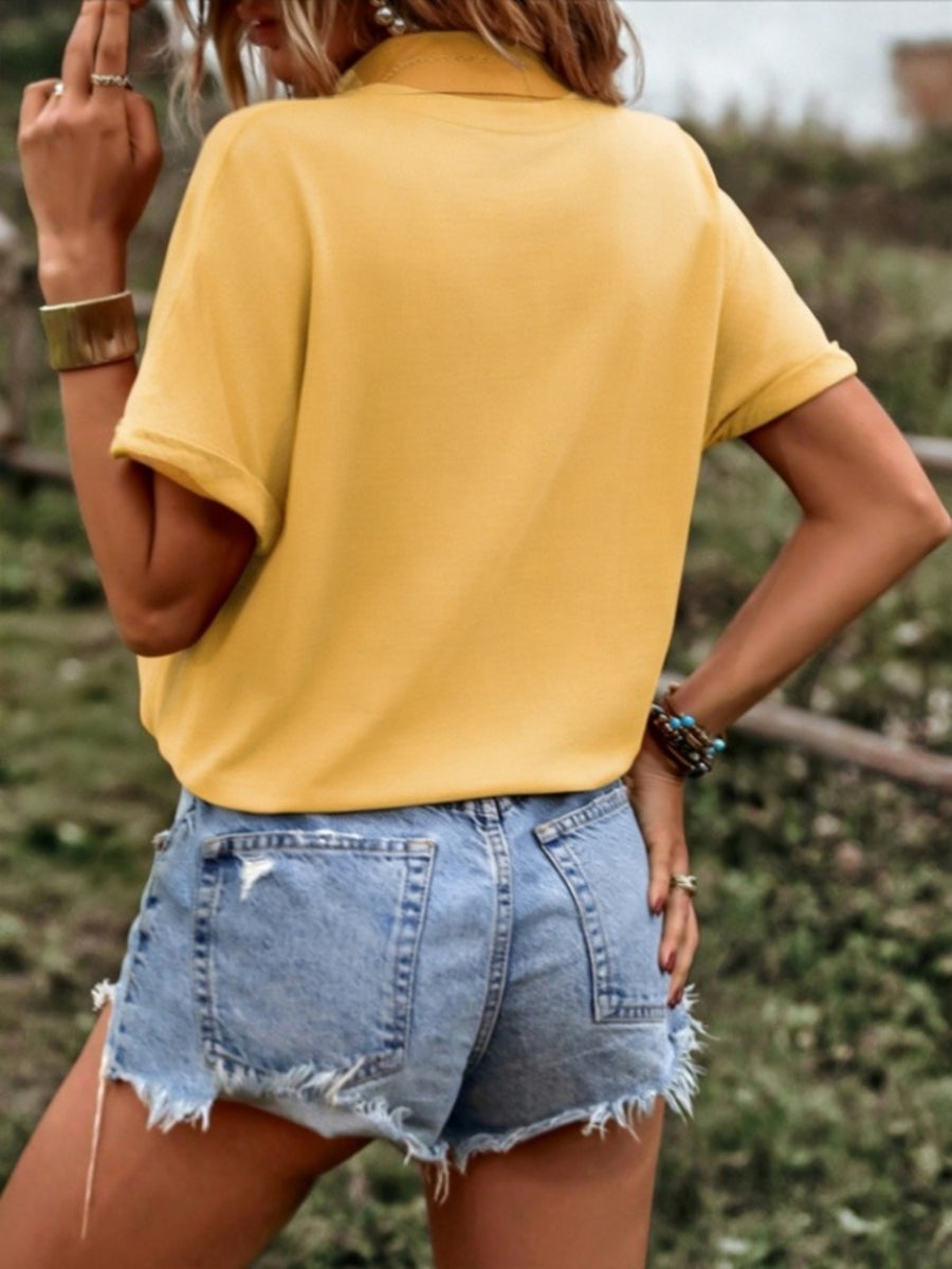 Yellow button-down shirt with drawstring hem and cuffed sleeves, styled with denim shorts.