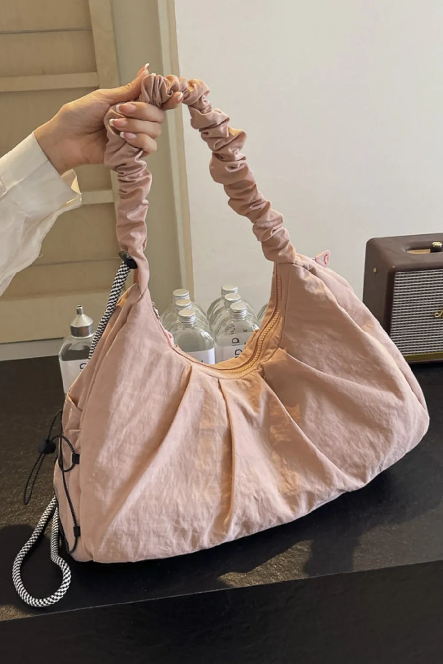 Gathered crescent shoulder bag in light pink with ruched strap and braided detail
