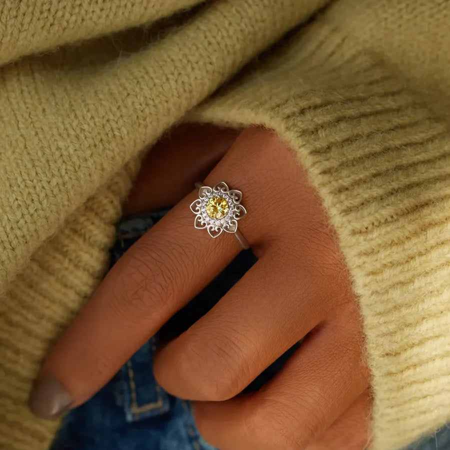 Silver ring with floral filigree and yellow zirconia center stone.