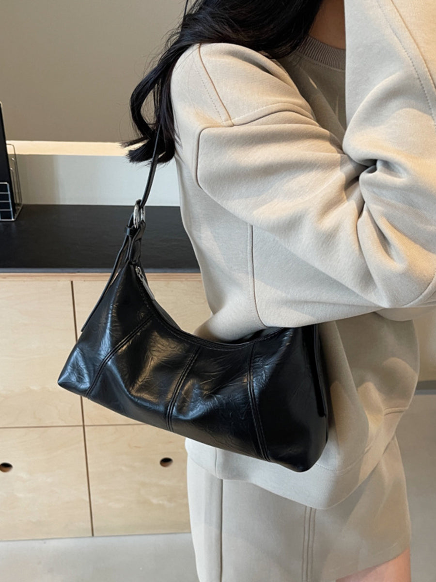 handbag in black featuring zipper closure and relaxed fit