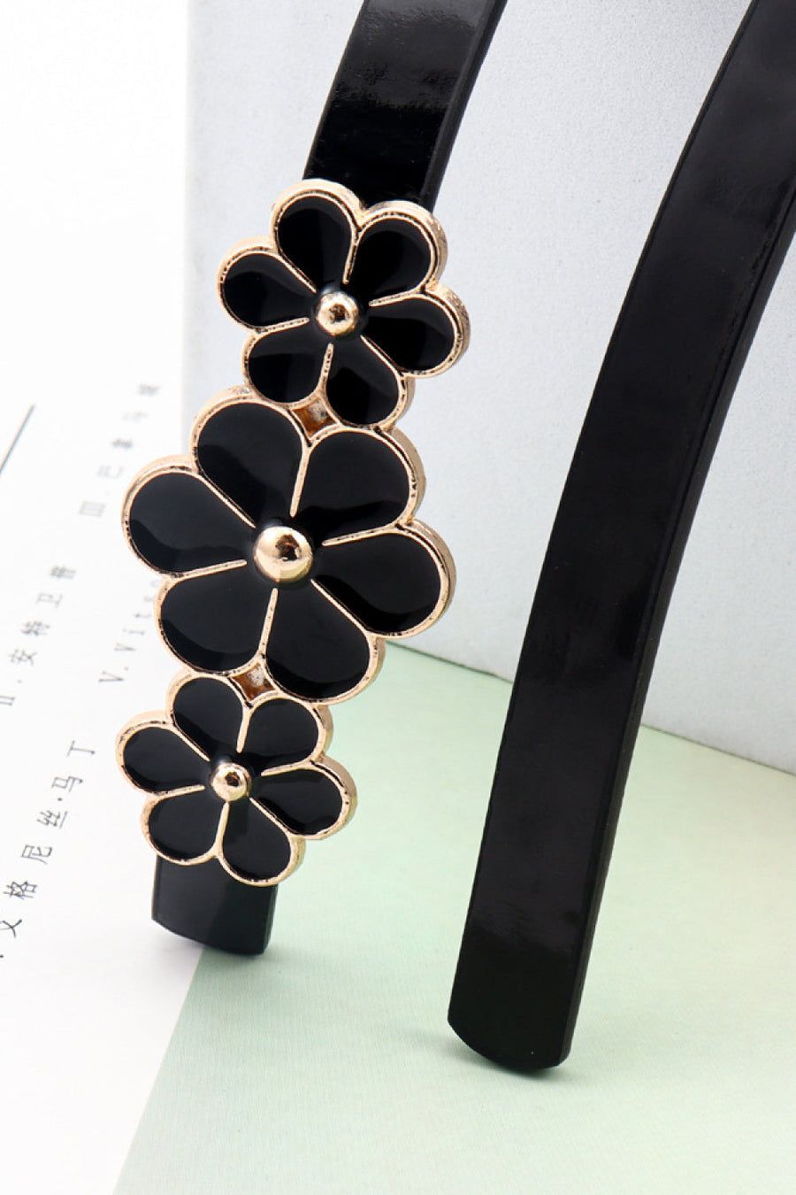 Black skinny belt with gold trim and black floral blossom embellishments.
